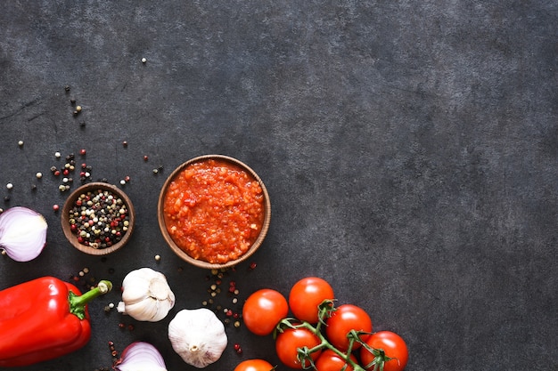 Salsa di pomodoro con pepe e aglio su uno sfondo scuro di cemento.