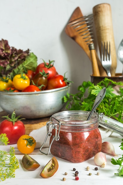 Salsa di pomodoro e pomodori freschi, aglio, aneto, prezzemolo su uno sfondo in legno chiaro ancora