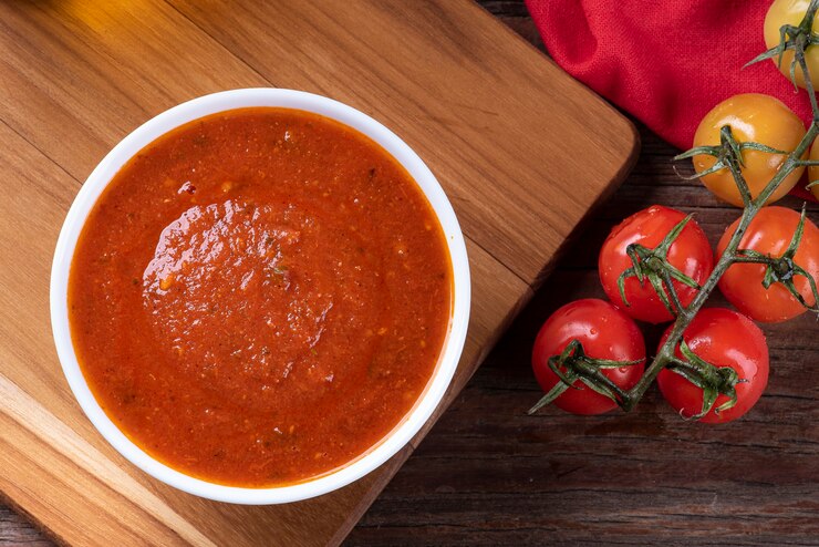 Foto salsa di pomodoro fresca deliziosa in una ciotola bianca. scenario decorato con pomodori. copia spazio. vista in alto