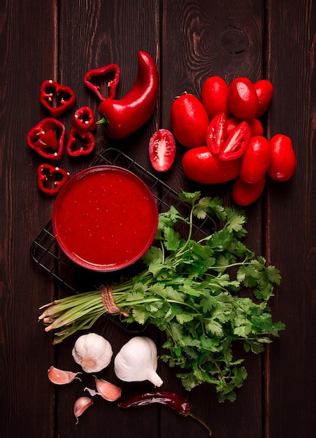 Salsa di pomodoro pomodori e peperoni Salsa Satsebeli georgiana con ingredienti su sfondo scuro vista dall'alto primo piano senza persone