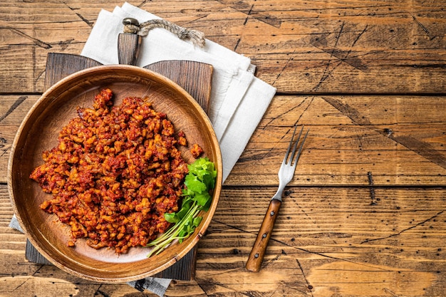 Salsa di pomodoro tradizionale italiana alla bolognese con carne macinata in un piatto di legno con erbe Sfondo in legno Vista dall'alto Spazio di copia