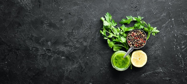 Salsa di prezzemolo verde olio d'oliva e spezie Ingredienti per salsa chimichurri su sfondo nero Vista dall'alto spazio libero per il testo