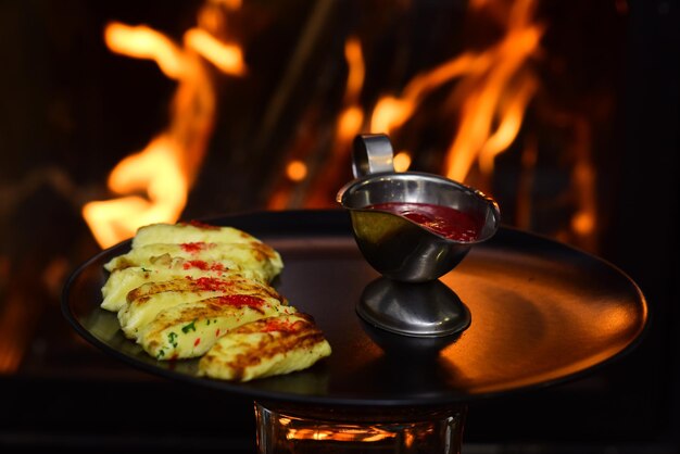 Salsa di tuffo servita all'alimento su sfondo di fuoco ardente. Tuffo di bacche di frutta rossa in casseruola. Non è mai troppo piccante