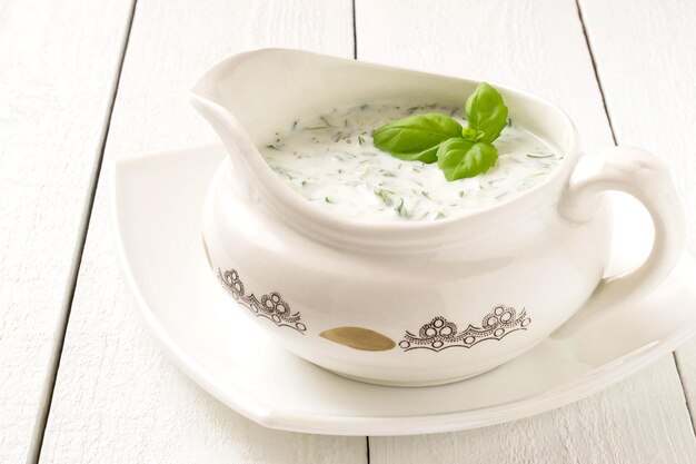 Salsa greca Tzatziki con yogurt, cetrioli, aglio e aneto su un tavolo di legno bianco