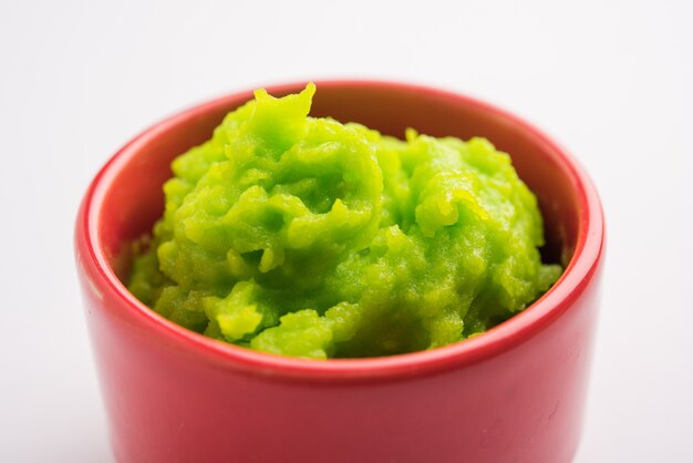 Salsa o pasta di wasabi verde in una ciotola, con le bacchette o un cucchiaio su uno sfondo colorato. messa a fuoco selettiva