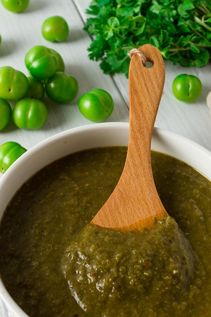 Salsa tkemali cucina georgiana tradizionale prugna verde ciliegia su un tavolo di legno bianco primo piano cibo rustico sfondo nessun fuoco selettivo delle persone