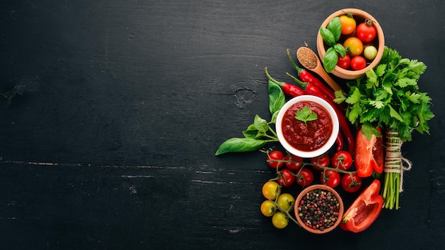 Salsa tradizionale al ketchup di pomodoro Pomodorini spezie peperoncino olio d'oliva prezzemolo Vista dall'alto su fondo di legno nero Spazio libero