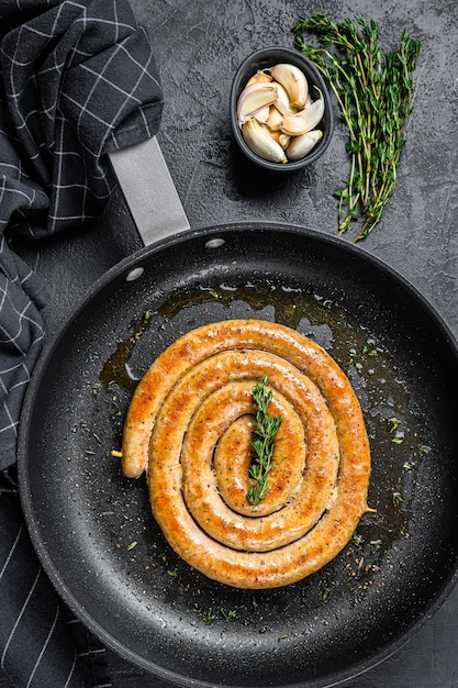 Salsicce a spirale alla griglia con aglio e condimento in padella.