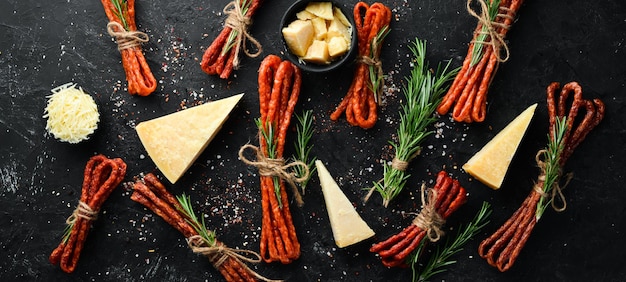 Salsicce affumicate con formaggio su fondo di pietra nera Parmigiano Kabanosy Vista dall'alto Spazio libero per il testo