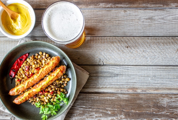 Salsicce alla griglia con lenticchie e peperoncino. Cucina tedesca. Birra.