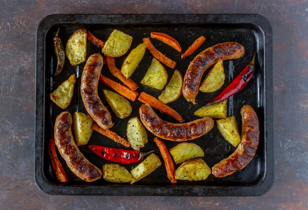 Salsicce alla griglia con patate, carote e peperoncino. Cucina tedesca.