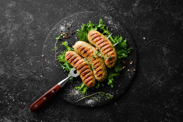 Salsicce alla griglia con rosmarino e spezie su una forchetta da barbecue Vista dall'alto su sfondo nero