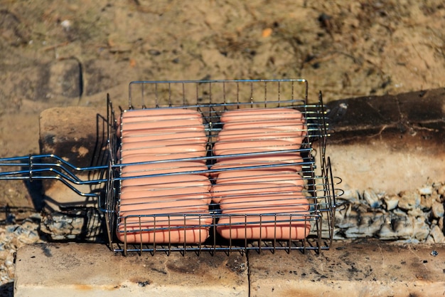 Salsicce alla griglia nella griglia del barbecue che cucinano sul fuoco