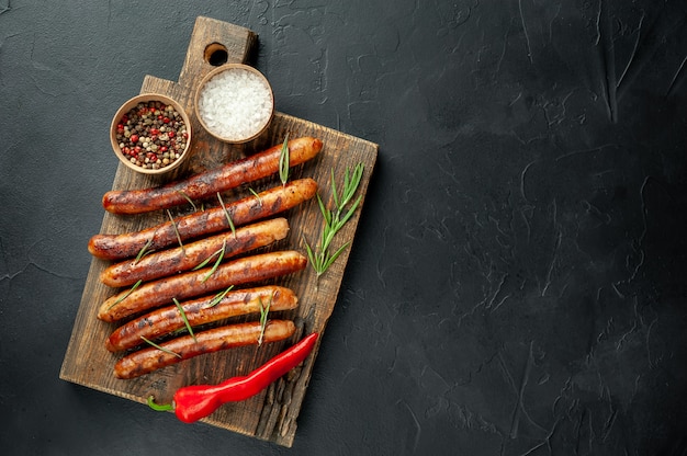 salsicce alla griglia su un tagliere con spezie e rosmarino su un tavolo di pietra con spazio di copia per il testo