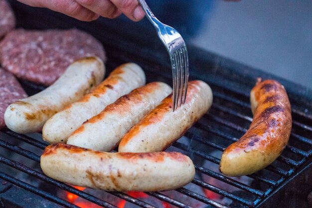 Salsicce alla griglia sulla griglia del barbecue. Messa a fuoco selettiva.