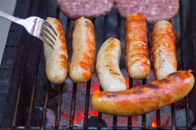 Salsicce alla griglia sulla griglia del barbecue. Messa a fuoco selettiva.