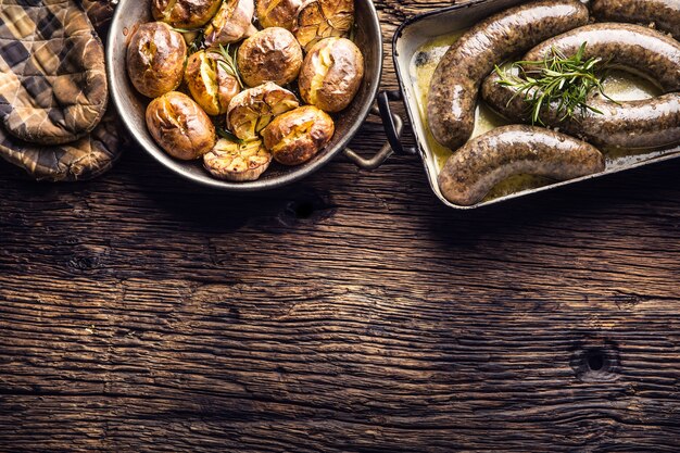 Salsicce arrosto in padella con rosmarino e patate... Cibo tradizionale europeo bratwurst jaternice o jitrnice.