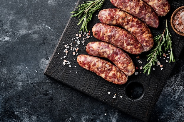 Salsicce crude o bratwurst sul tagliere con spezie e ingredienti per cucinare. Vista dall'alto con copia spazio sul tavolo in pietra.