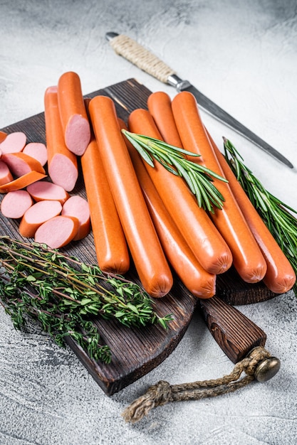 Salsicce crude tedesche di Frankfurter su una tavola di legno. Sfondo bianco. Vista dall'alto.