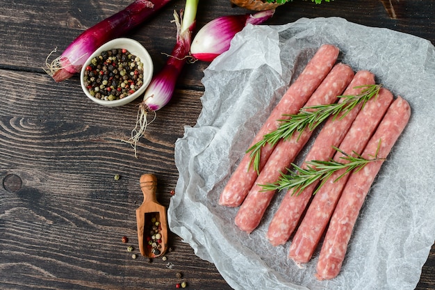 salsicce di carne cruda per barbecue o hot dog. cipolle viola, sale e pepe, origano fresco per la marinata. cena in famiglia alla griglia