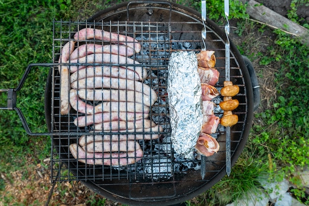 Salsicce di carne, funghi al bacon e pesce al cartoccio vengono cotti sul fuoco