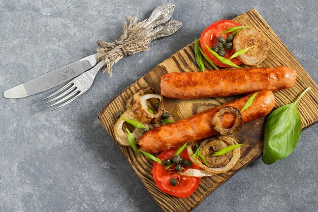 Salsicce e verdure fritte sul piatto di legno