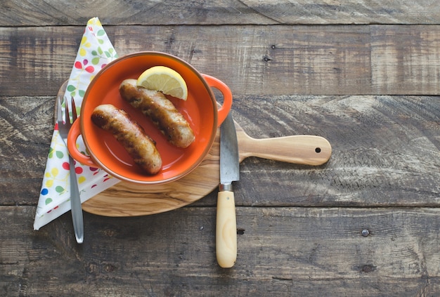 Salsicce fritte con una fetta di limone in una ciotola di ceramica