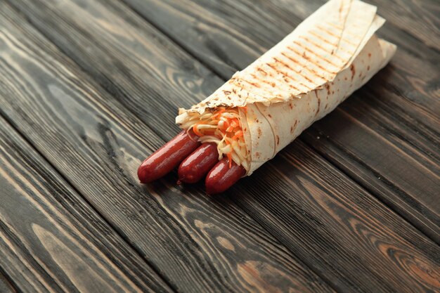 Salsicce piccanti in pane pita su sfondo di legno con poliziotto