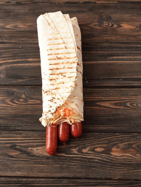 Salsicce piccanti in pane pita su sfondo di legno con poliziotto