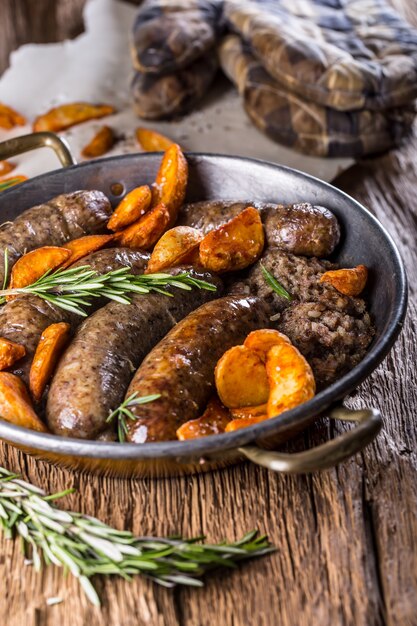 Salsicce.Salsiccia di maiale arrosto in padella con patate e rosmarino.