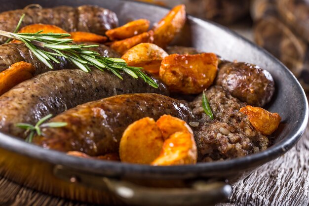 Salsicce.Salsiccia di maiale arrosto in padella con patate e rosmarino.