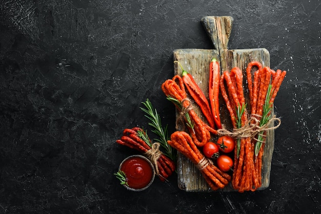 Salsicce secche con peperoncino su sfondo di pietra nera Peperoni cileni Kabanosy Vista dall'alto Spazio libero per il testo