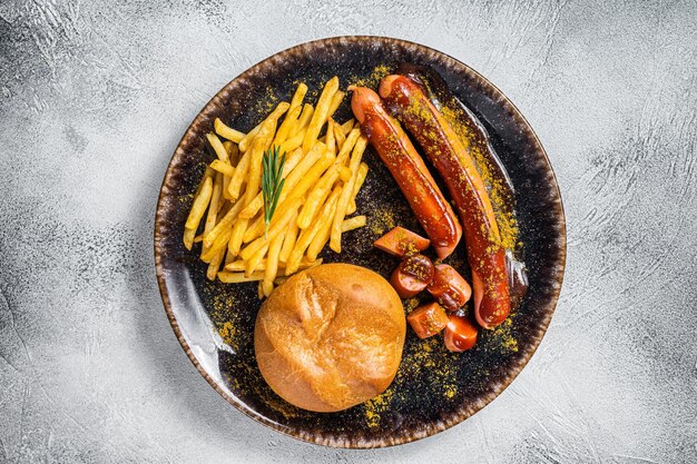 Salsicce Surrywurst pezzi di salsiccia con salsa al curry e patatine fritte Sfondo bianco Vista dall'alto