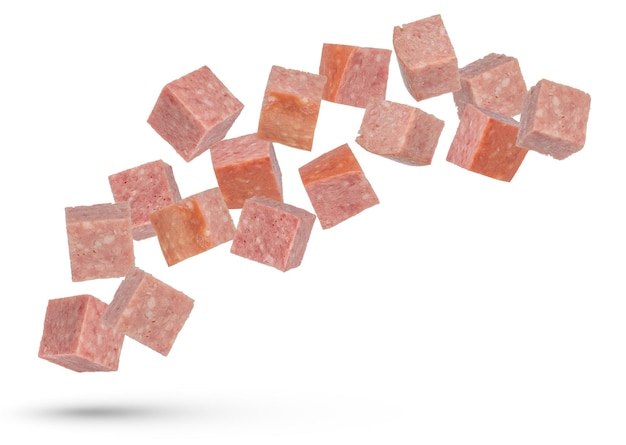 Salsicce volanti Cubi di salsicce affumicate su uno sfondo bianco isolato Cubi di Salami cadono su uno sfonto bianco per l'inserimento in un progetto o progetto