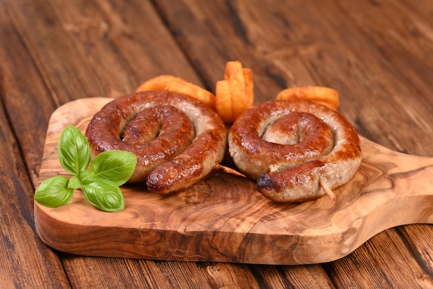 Salsiccia a spirale piccante arrosto con foglie di basilico e patatine fritte