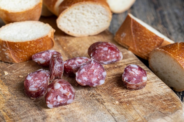 salsiccia affettata con baguette su un tagliere di legno, salsiccia di maiale fatta in casa affettata con baguette di grano su un tagliere