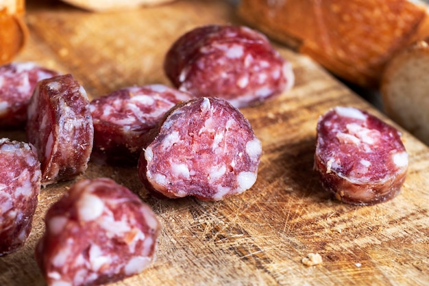 Salsiccia affettata con una baguette su una tavola di legno