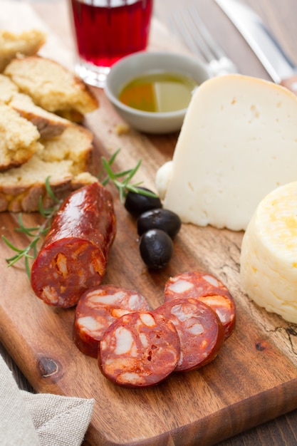 Salsiccia affumicata, formaggio, pane e bicchiere di vino rosso