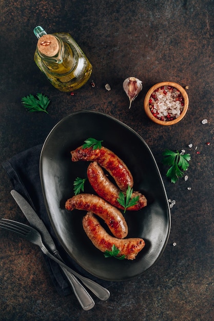 Salsiccia alla griglia con verdure su piatto nero su sfondo scuro Vista dall'alto con spazio per la copia Foto verticale