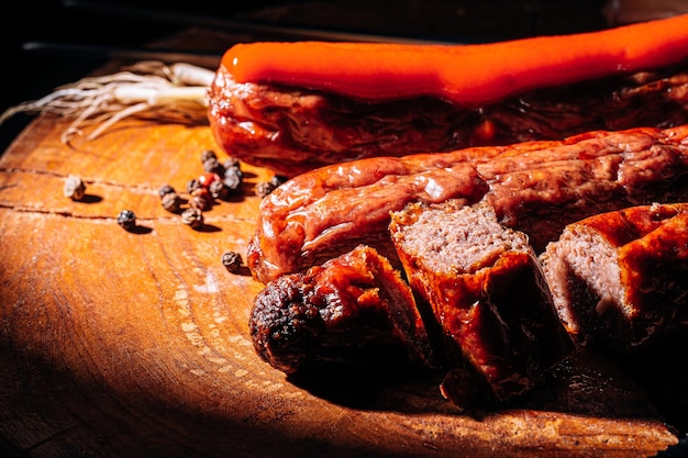 Salsiccia alla griglia su fondo scuro su una superficie di legno con spezie e salsa