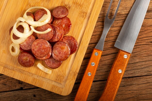 Salsiccia calabrese affettata con cipolla su fondo di legno