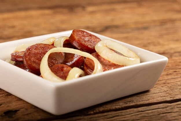 Salsiccia calabrese affettata con cipolla su fondo di legno