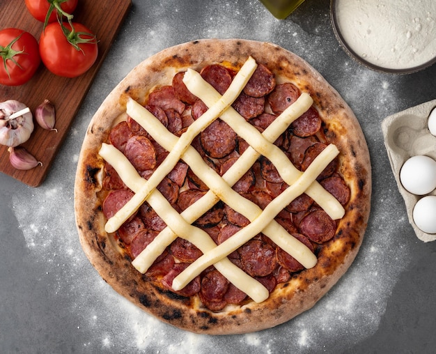 Salsiccia calabrese e formaggio a crema Catupiry pizza sfondo in pietra con pomodori olive e oregano