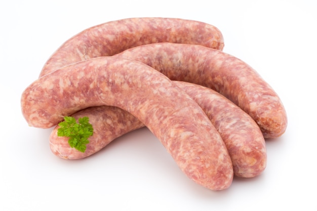 Salsiccia cruda con foglia di prezzemolo isolato su sfondo bianco.