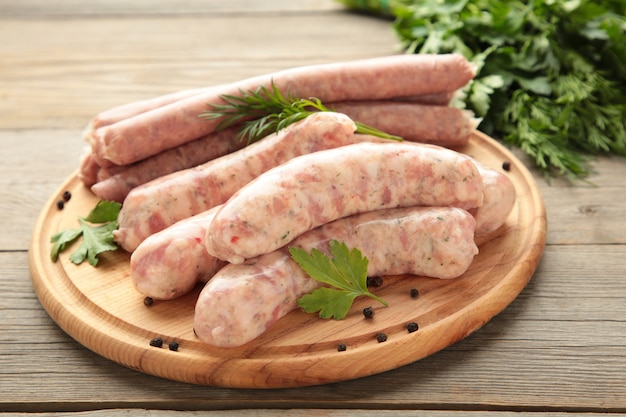 Salsiccia cruda sul tagliere su superficie di legno grigia