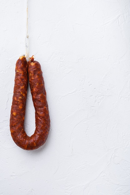 Salsiccia di chorizo spagnolo sulla superficie strutturata bianca con lo spazio della copia.