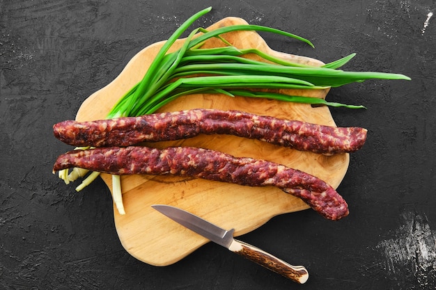 Salsiccia di maiale essiccata al sole sul tagliere di legno