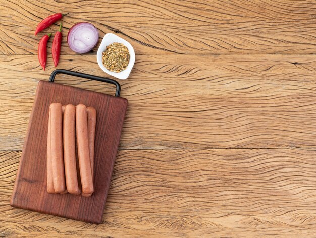 Salsiccia di maiale sottile su tavola di legno con condimenti e copia spazio.