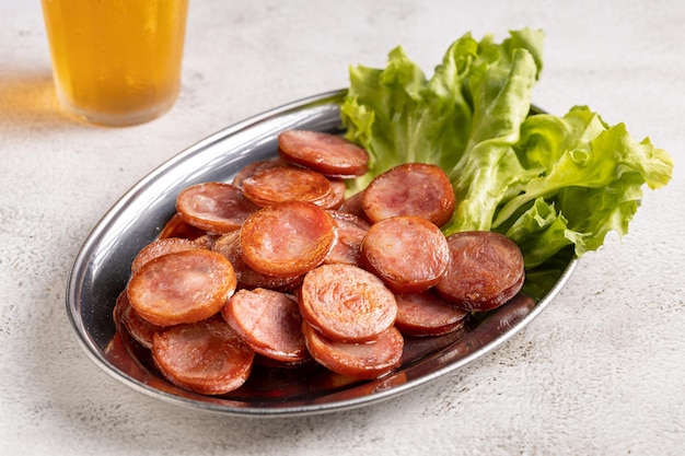 Salsiccia di peperoni fritta a fette con un bicchiere di birra sul tavolo