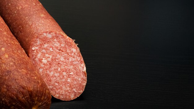 Salsiccia di salame affumicata su tavola di legno nera